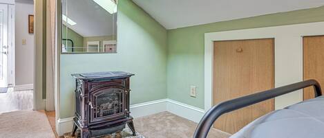 A room with a skylight, a vintage stove, a bed, and a door.
