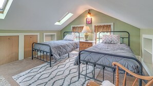A bedroom with two beds, a skylight, a lamp, and a window with curtains. - Quaint & Charming Cherry Valley Escape! (Cherry Valley)