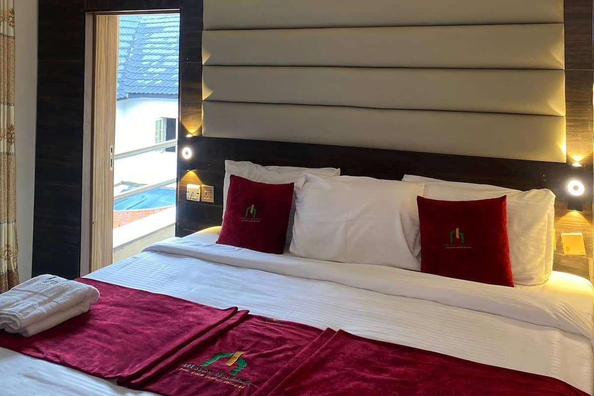 A hotel room with a large bed, dark wall paneling, and a window with a view of a blue-roofed building.