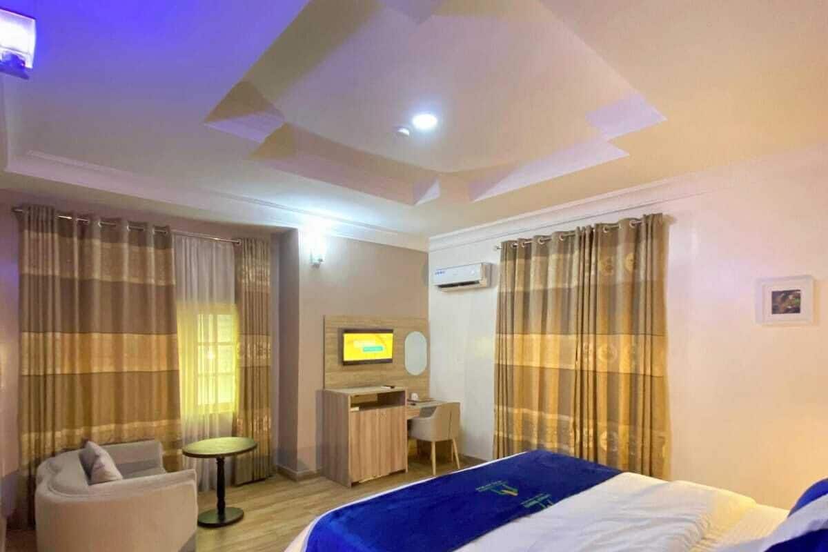 A hotel room with a large bed, a desk, a chair, and a sofa.