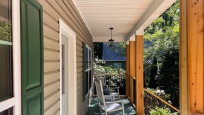 A covered porch with two rocking chairs and a potted plant. - Charming 3BR Cottage w/ Full Kitchen, Community amenities, Patio, and Gas Grill (Newland)