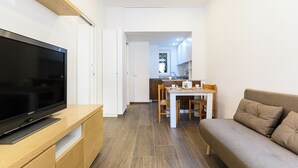 Una sala de estar moderna con un televisor de pantalla plana, un sofá y una zona de comedor con mesa y sillas.