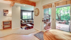 A spacious living room with a wooden ceiling, a large wall clock, and a view of the outdoor deck. - Hot Tub & Mtn Views: Charming Utah Canyon Retreat (Sandy)