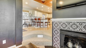A modern kitchen with wooden beams, a fireplace, and a dining area with chairs and a table. - Hot Tub & Mtn Views: Charming Utah Canyon Retreat (Sandy)