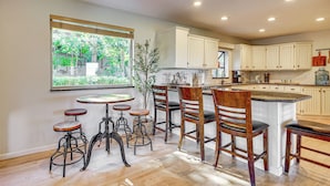 A kitchen with wooden cabinets, a central island, and bar stools. - Hot Tub & Mtn Views: Charming Utah Canyon Retreat (Sandy)