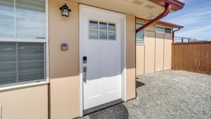 Un edificio color beige con puerta y ventanas blancas, y un pequeño porche.