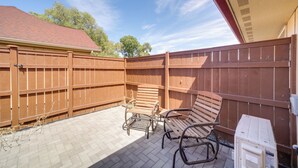 Ein Patio mit Holzlattenzaun, zwei Metallstühlen und einem kleinen Tisch.