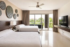 Une chambre d’hôtel avec deux lits, une télévision, un ventilateur de plafond et un balcon avec vue.