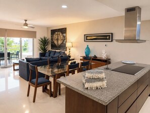 Une cuisine moderne avec un îlot central, un coin repas avec des chaises, un canapé et une grande fenêtre.