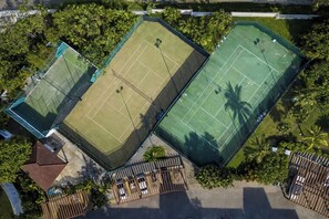 Vue aérienne d’un complexe sportif comprenant plusieurs courts de tennis, le tout entouré de verdure.