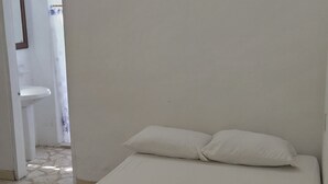 Un dormitorio con cama, mesita de noche y lámpara de pared.