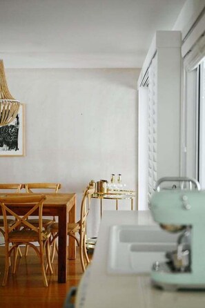 Un comedor con una mesa y sillas de madera, una mesita con botellas y una lámpara colgante.