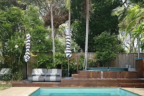 Un patio trasero con piscina, jacuzzi y terraza de madera.