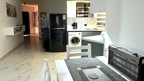A modern kitchen with a built-in oven, a refrigerator, and a washing machine. There is a dining area with a table and chairs. - Modern 2-Bedroom flat in prime compound with pool & all  Amenities (Red Sea Governorate)