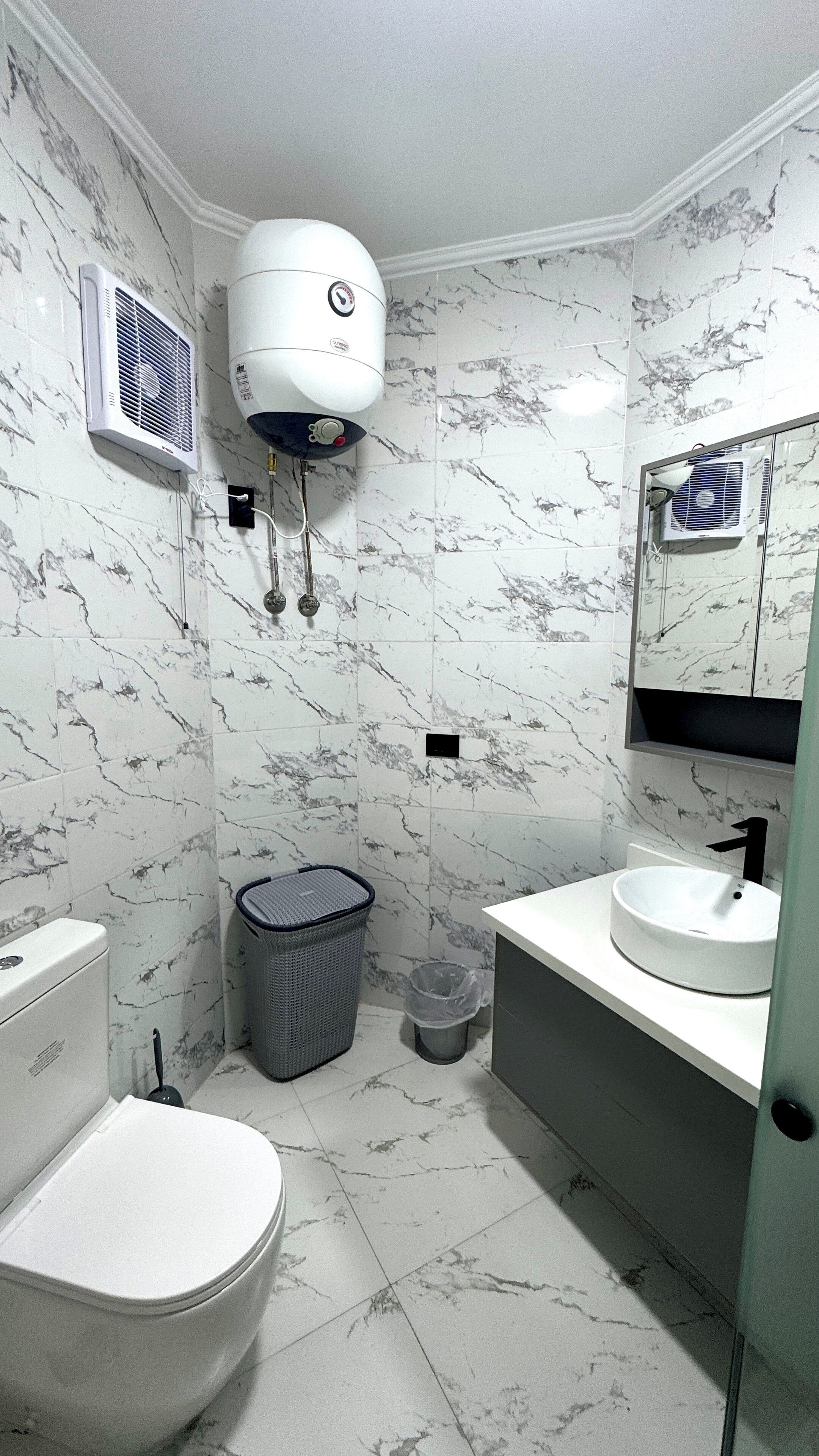 Een badkamer met toilet, wastafel en spiegel.