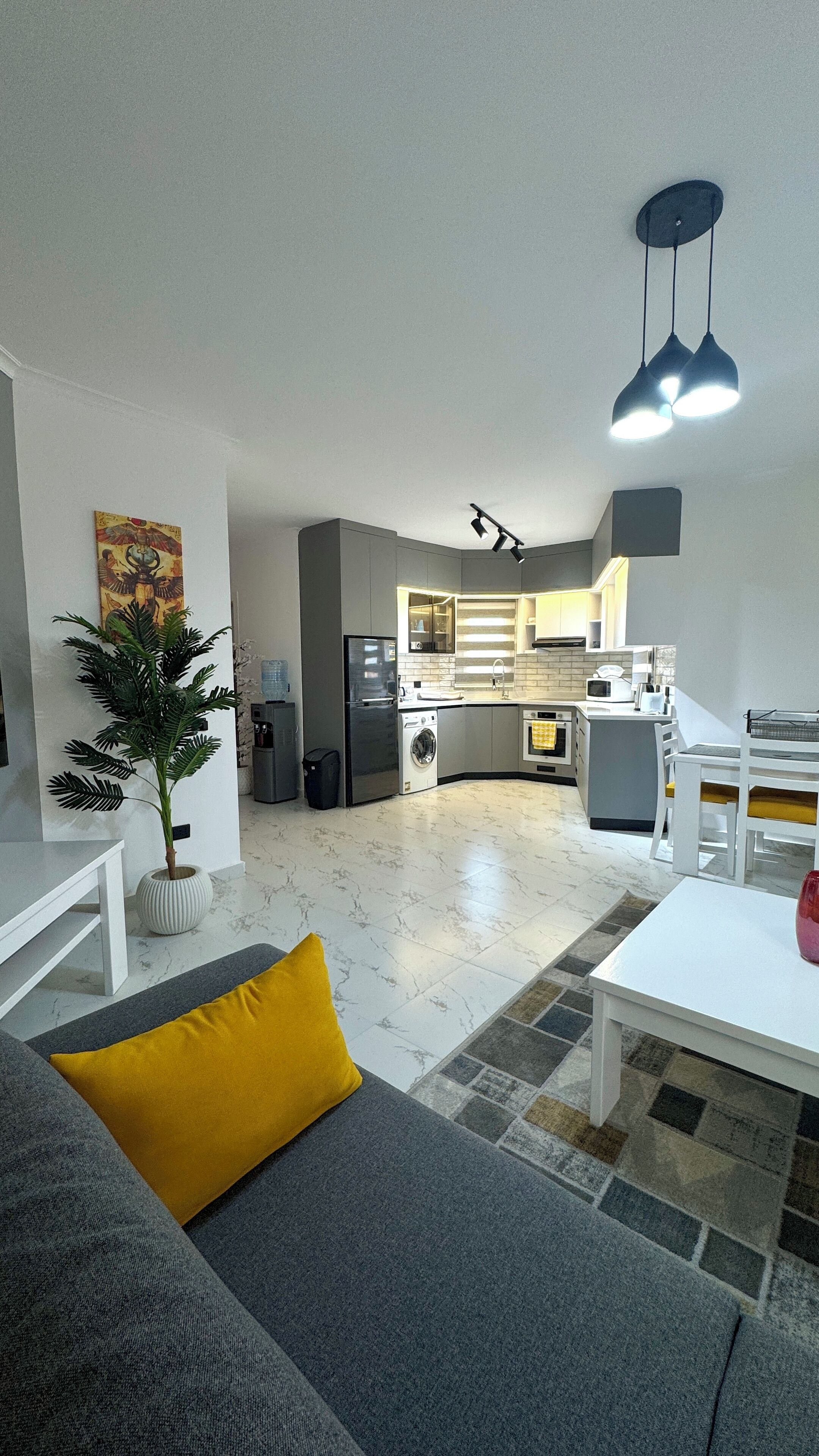 Een moderne woonkamer met een bank, een eettafel en een keuken op de achtergrond.