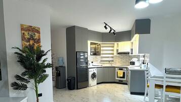 Een moderne woonkamer met een bank, een eettafel en een keuken op de achtergrond.