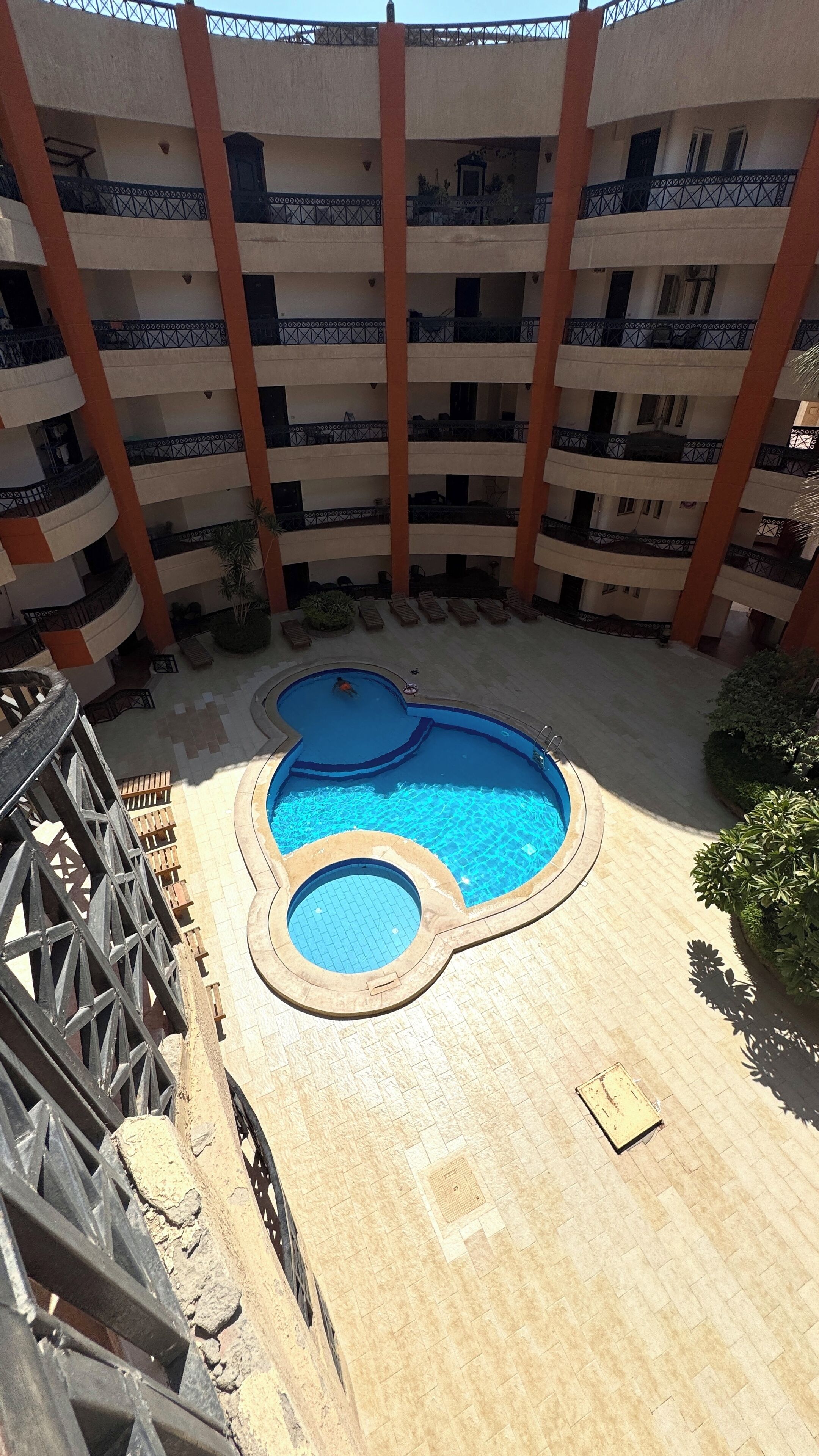 Ein mehrstöckiges Gebäude mit einem zentralen Innenhof und einem Schwimmbad.