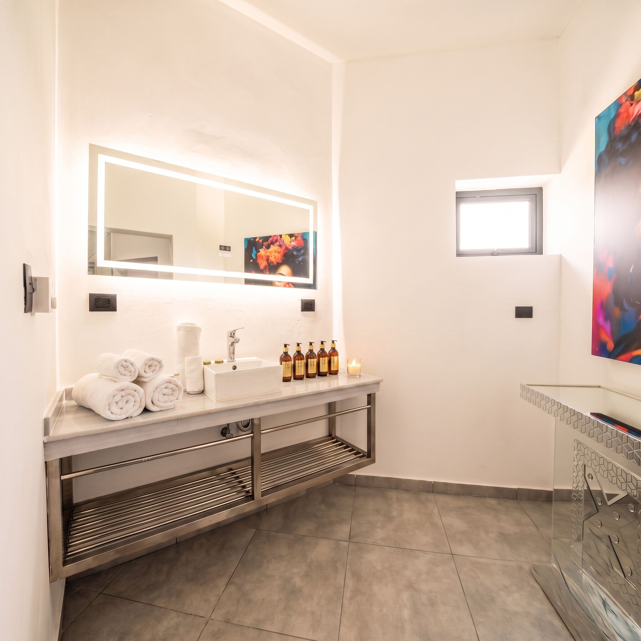 Une salle de bain moderne avec un grand miroir, un meuble-lavabo et des serviettes soigneusement rangées.