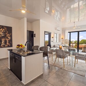A modern kitchen with a central island, a dining area with a glass table, and a living room with a view. - 2BR at Rizz Suites • Pool • 24/7 GYM • Walk to Beach • 2 King Beds • Sosua (Sosúa)