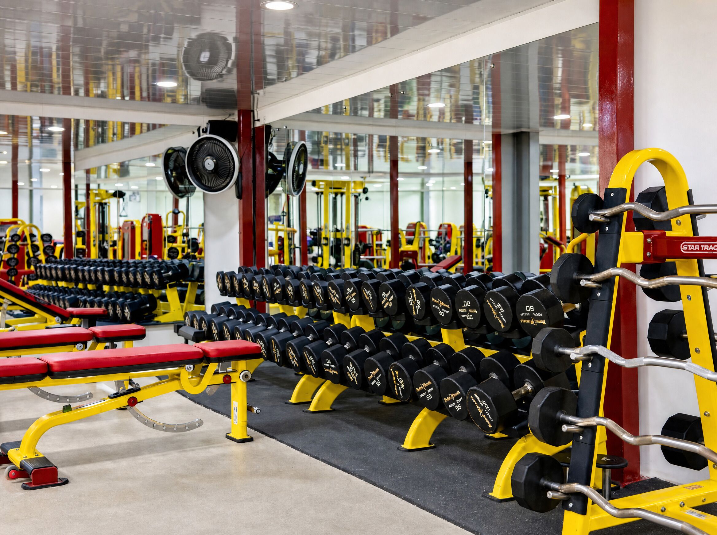 A gym with various weightlifting equipment, including dumbbells and benches.