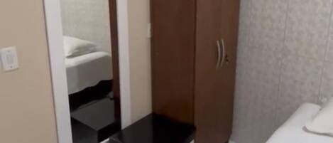 Una camera da letto con un letto, un armadio, uno specchio e un condizionatore d'aria.
