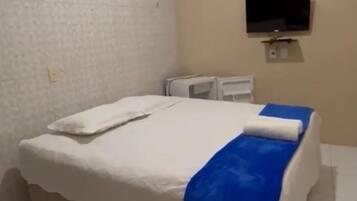A hotel room with a bed, a TV mounted on the wall, and a small desk.