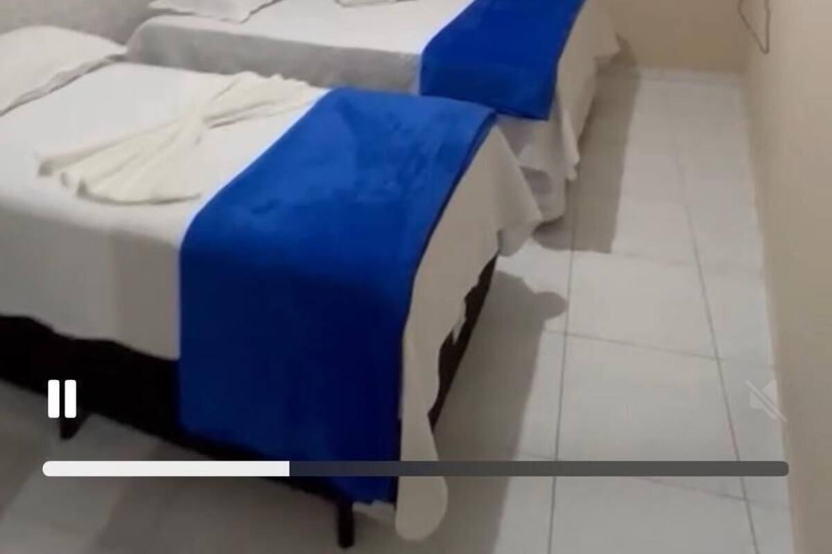 A small, clean room with two beds, each with a blue blanket.
