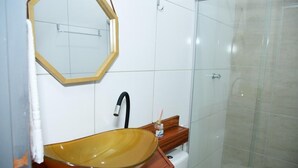 A bathroom with a large oval sink, a mirror, and a shower area. - Pousada Aconchego da Serra (Martins)