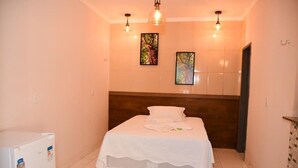 A small, neatly arranged bedroom with a single bed, a wooden headboard, and two wall-mounted light fixtures. - Pousada Aconchego da Serra (Martins)