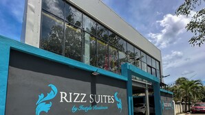 A building with a sign reading "RIZZ SUITES by Instyle Residences" and a blue awning. - Cozy 1BR suite at Rizz Suites – GYM, Pool, A/C & Walk to Beach (Sosúa)