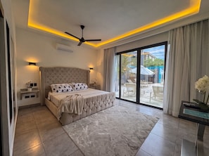 Une chambre à coucher avec un lit, un ventilateur de plafond et une vue sur l’extérieur grâce à de grandes portes coulissantes.
