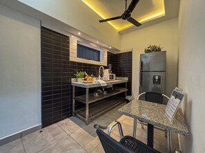 Cocina compacta con microondas incorporado, refrigerador y una zona de comedor con una silla.
