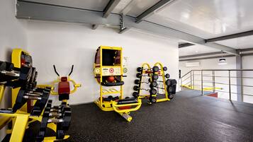 Een sportschool met gewichthefapparatuur, een bankdrukpers en een power rack.