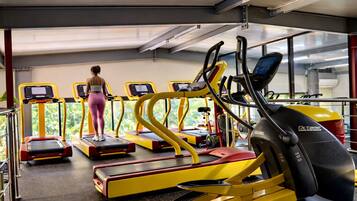 Un gimnasio con cintas de correr, elípticas y una bicicleta estática, con una persona ejercitándose.