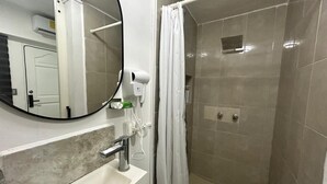 A bathroom with a white sink, a mirror, a shower with a curtain, and a towel rack.