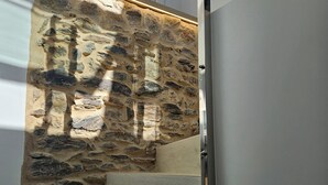 Una escalera con paredes de piedra y barandilla de vidrio.