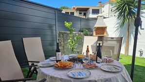 Mobiliario de comedor al aire libre con una mesa cubierta con mantel de encaje, rodeado de sillas.