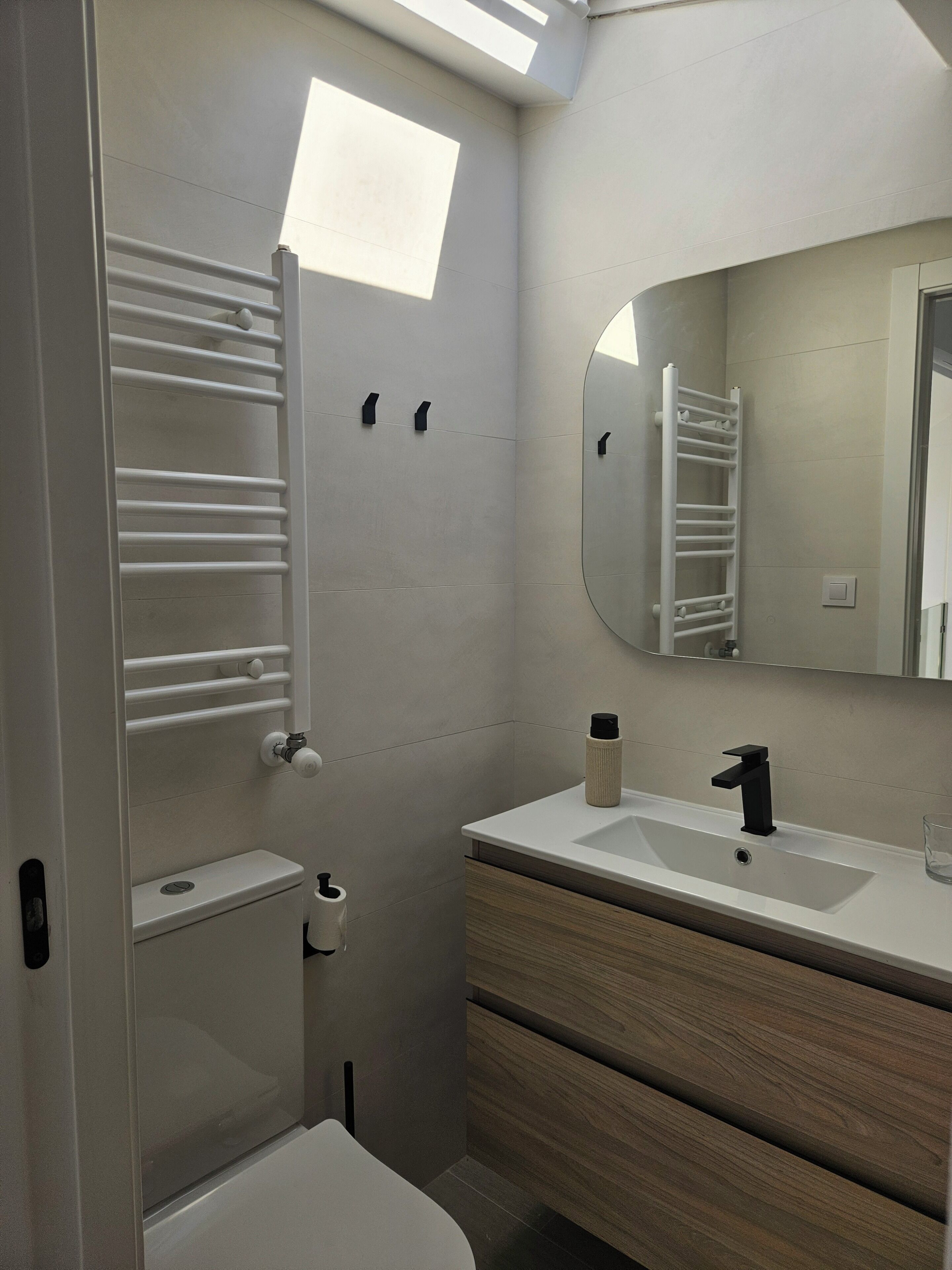Un baño moderno con inodoro, lavamanos y espejo.