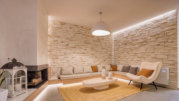 Een moderne woonkamer met een stenen muur, een open haard, een zithoek, een salontafel en een lamp.