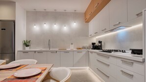 Een moderne keuken met witte kasten, een roestvrijstalen koelkast en een eethoek met een tafel gedekt voor twee personen.