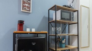 Une cuisine de taille réduite avec un réfrigérateur noir, une étagère pour micro-ondes et un petit placard.
