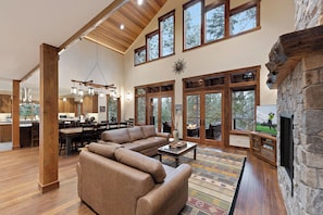 A spacious living room with a large sectional sofa, a fireplace, and a stone wall.
