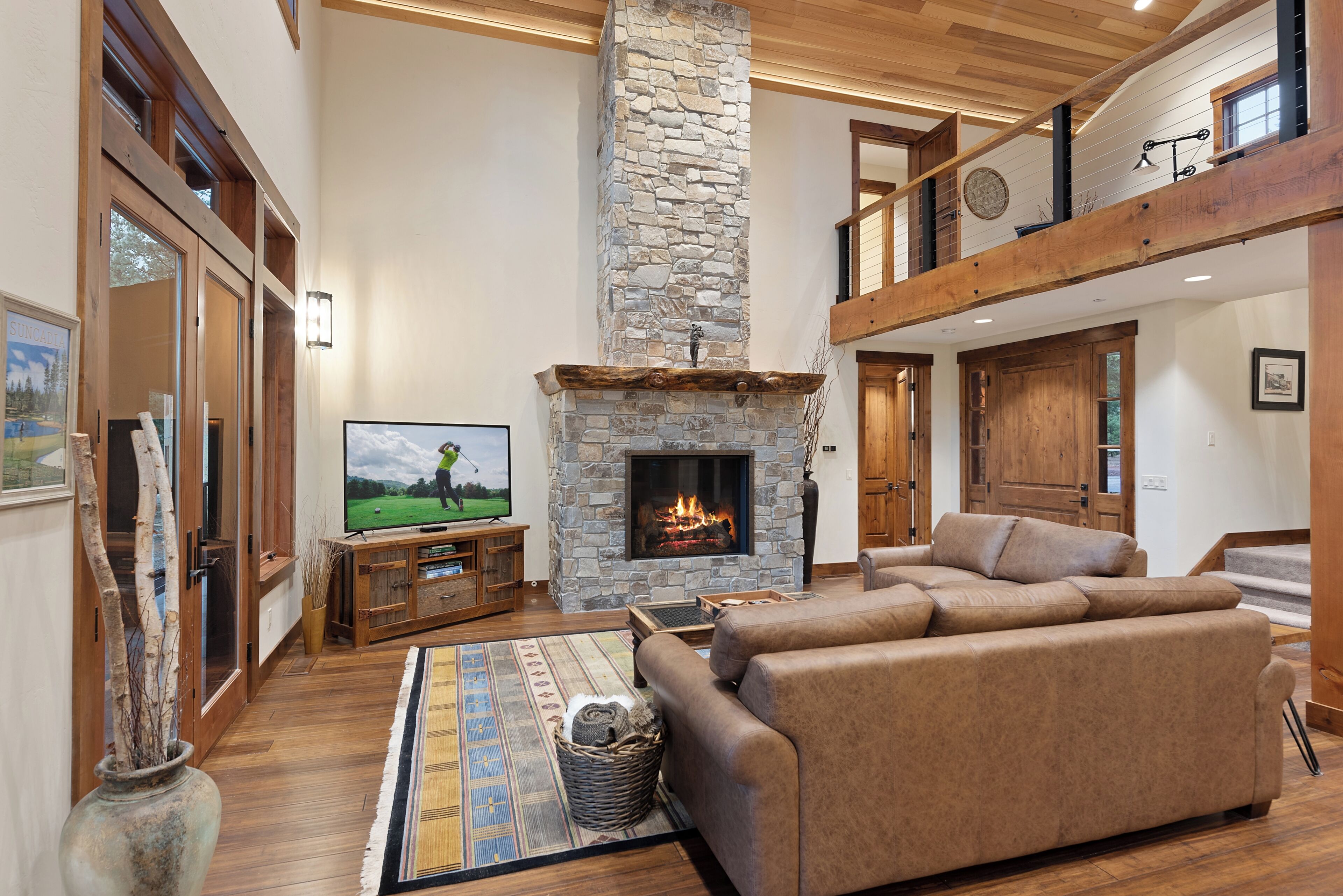 A spacious living room with a stone fireplace, a television, and a comfortable seating area.