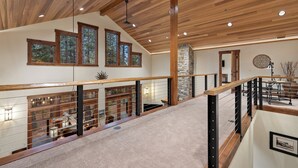 Un intérieur spacieux avec de hauts plafonds, des poutres en bois et une vue sur l’extérieur grâce à de grandes fenêtres.