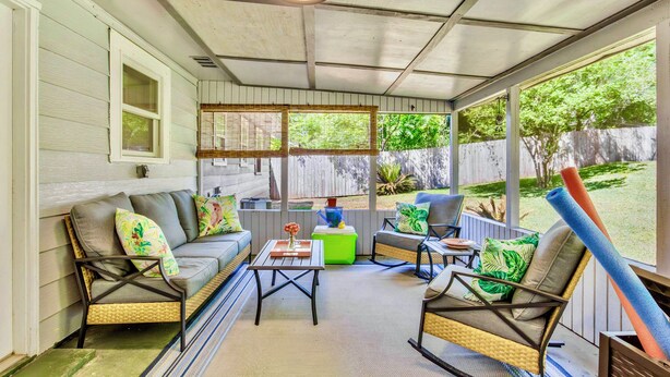 Eine überdachte Veranda mit einer Couch, Stühlen und einem Tisch.