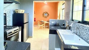 A compact kitchen with a gas stove, refrigerator, and a dining area with a table and chairs.