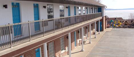 Un motel con estacionamiento techado y vista a un cuerpo de agua.
