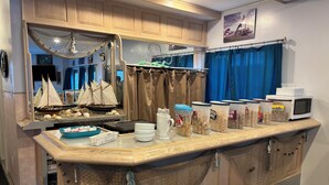 A kitchen with wooden cabinets, a breakfast bar, and a nautical theme with ship models and netting. - LEISURE INN (Temiskaming Shores)