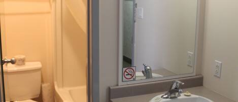 A bathroom with a toilet, bathtub, sink, and mirror.